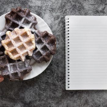 flat-lay-hand-holding-plate-waffles-notebook